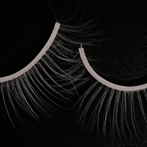 Prompt: A close-up of a pair of false eyelashes on a black background.